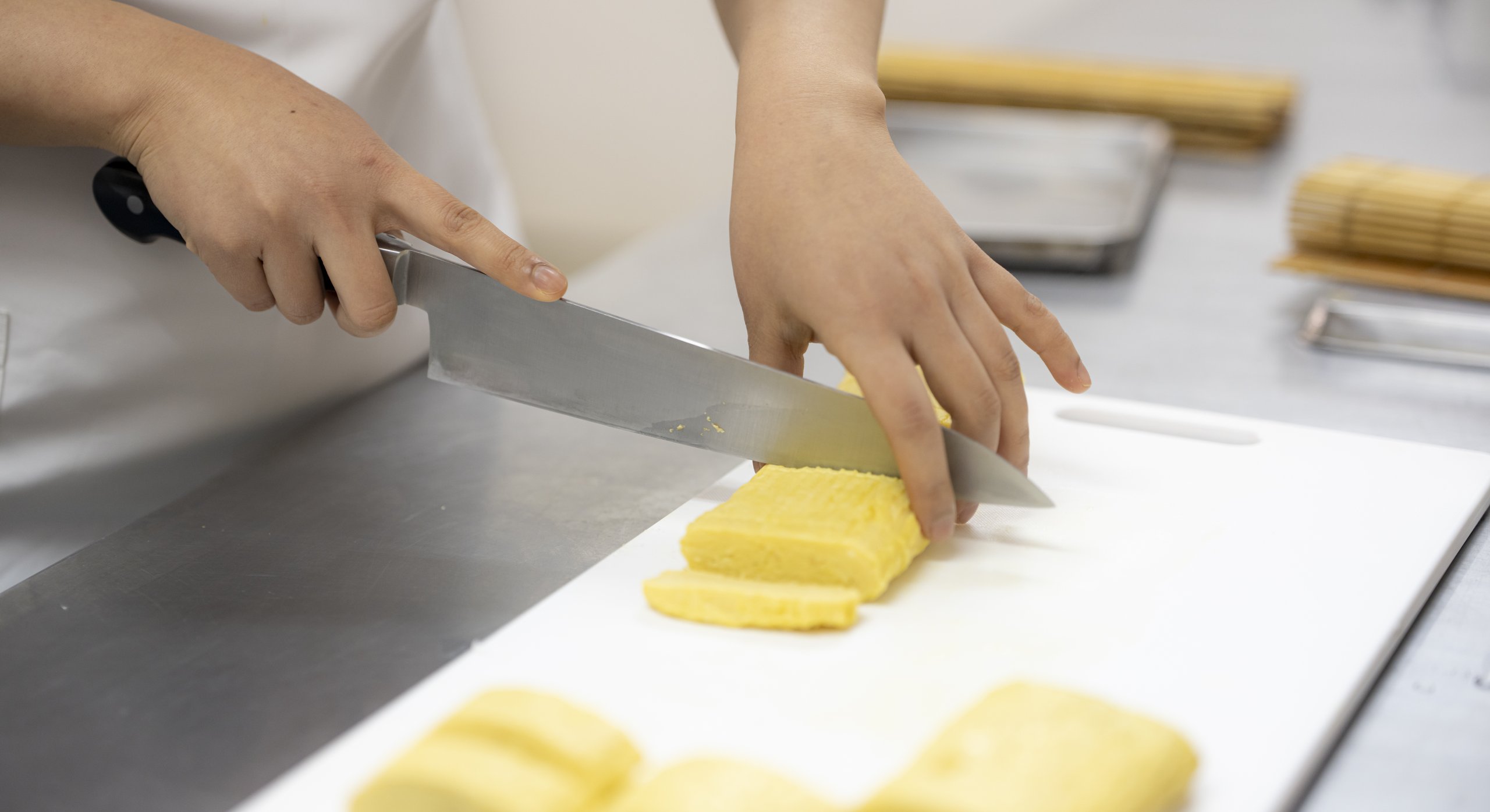 玉子焼きを包丁で切り分ける手元