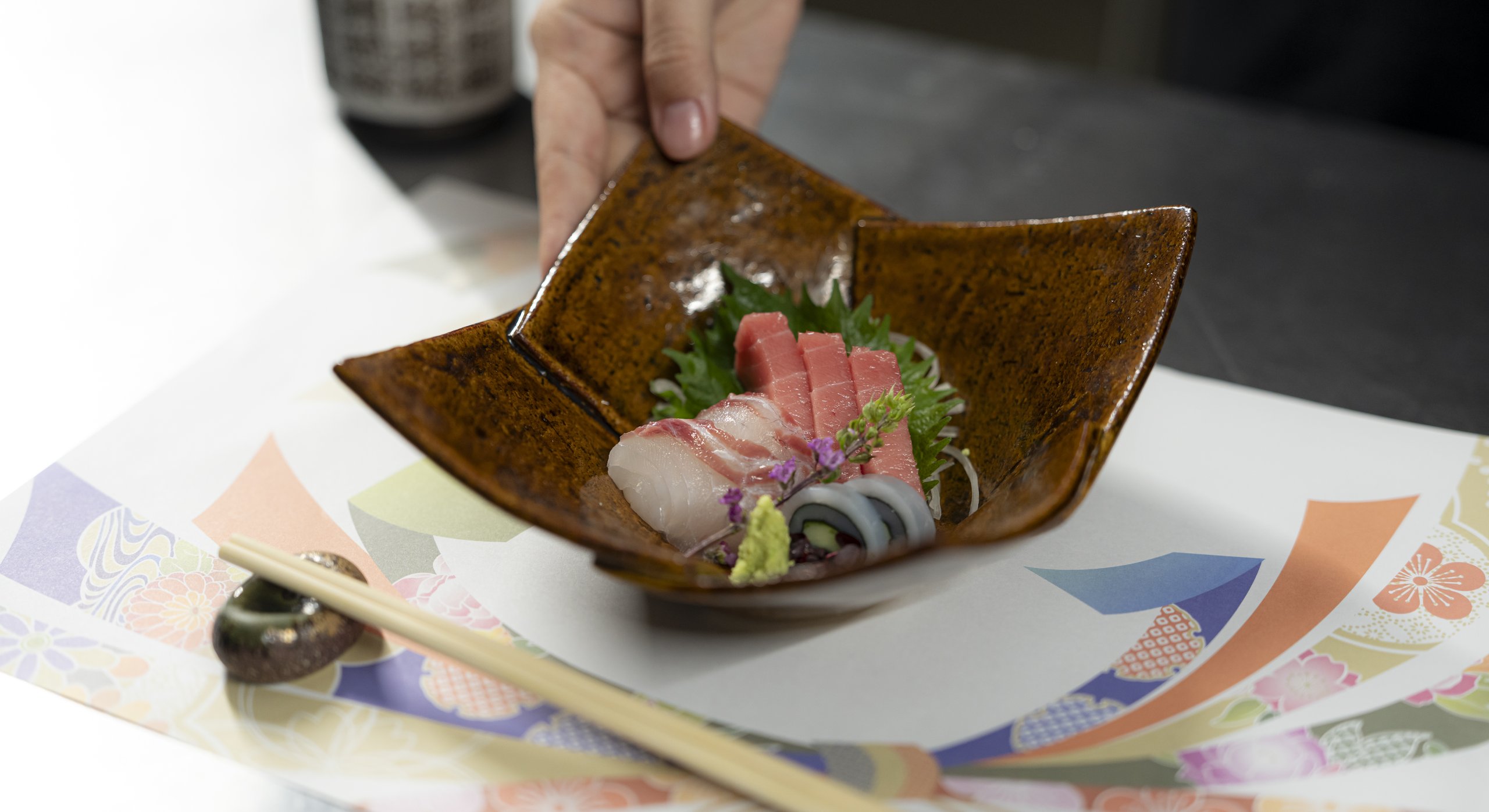 刺身を盛った器を差し出す手元